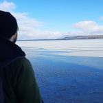 A man looking out into a bay of frozen lake water